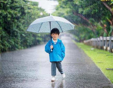 雨の日に傘をさして道路に立つ男の子 雨の日に傘をさして道路に立つ男の子の写真
