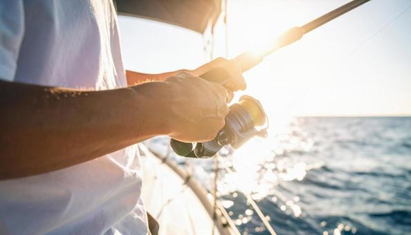 外洋でヨットで釣り竿を持っている男性の手 外洋でヨットで釣り竿を持っている男性の手の写真