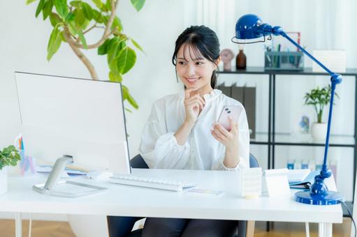 オフィスでスマホを持つビジネスウーマン スマホ,笑顔,ビジネスウーマンの写真素材