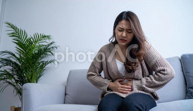 お腹の調子が悪くてお腹をさする若い女性 女性,お腹,不調の写真素材