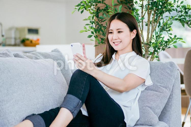 ソファでスマホを使う女性 スマホ,スマートフォン,女性の写真素材