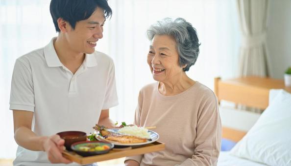 高齢女性と男性介護士の穏やかな食事風景 高齢女性と男性介護士の穏やかな食事風景の写真