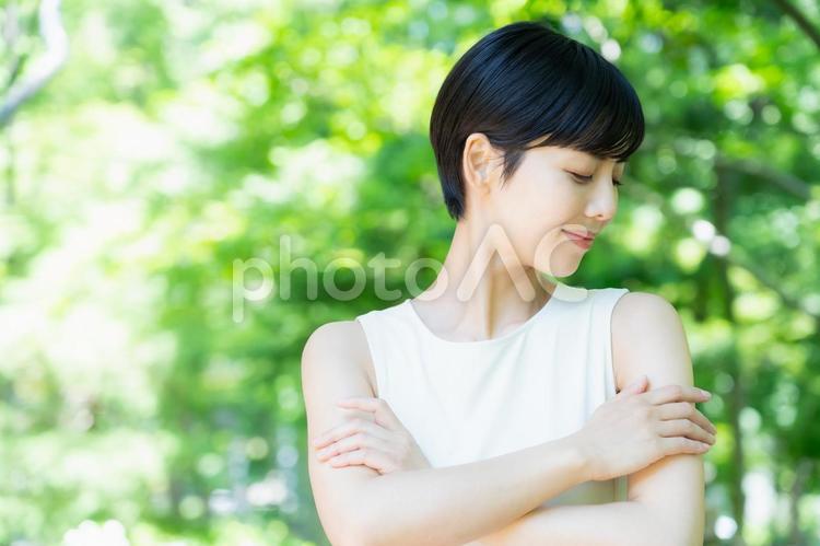 緑の中でスキンケアをする若い女性 スキンケア,ビューティー,女性の写真素材