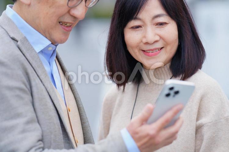 屋外でスマートフォンを使う高齢夫婦 夫婦,男性,女性の写真素材