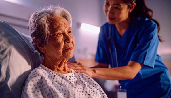 帰宅願望が強い高齢女性患者と励ます看護師の写真