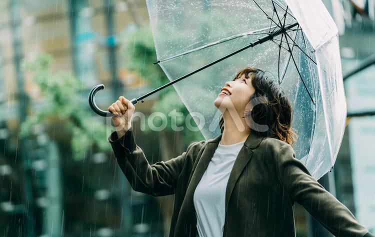 雨の中で傘をさす笑顔の女性（梅雨・6月） 雨,梅雨,6月の写真素材