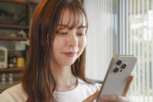 スマートフォンを操作する女性 女性,横顔,笑顔の写真素材