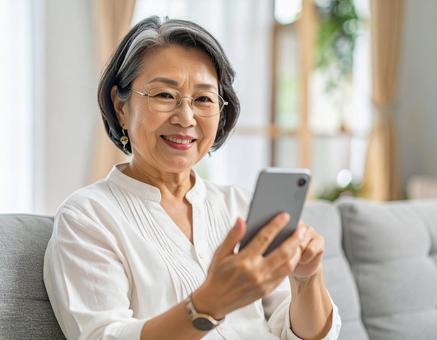 自宅のリビングでスマホを操作する女性 自宅のリビングでスマホを操作する女性の写真