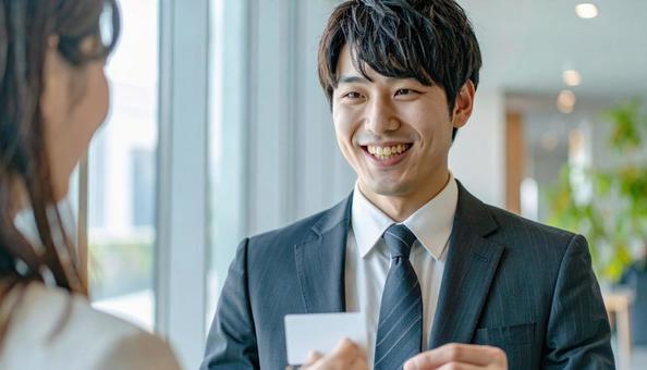 笑顔で名刺を差し出す男性社員の写真