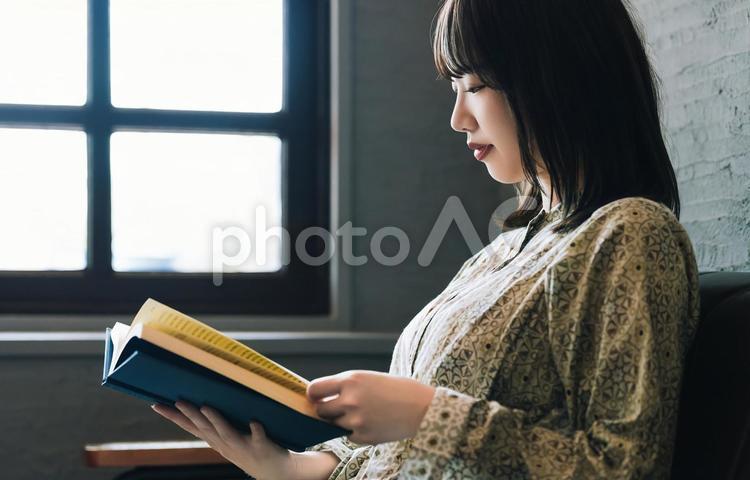 ソファに座って読書をする女性 女性,読書,本の写真素材