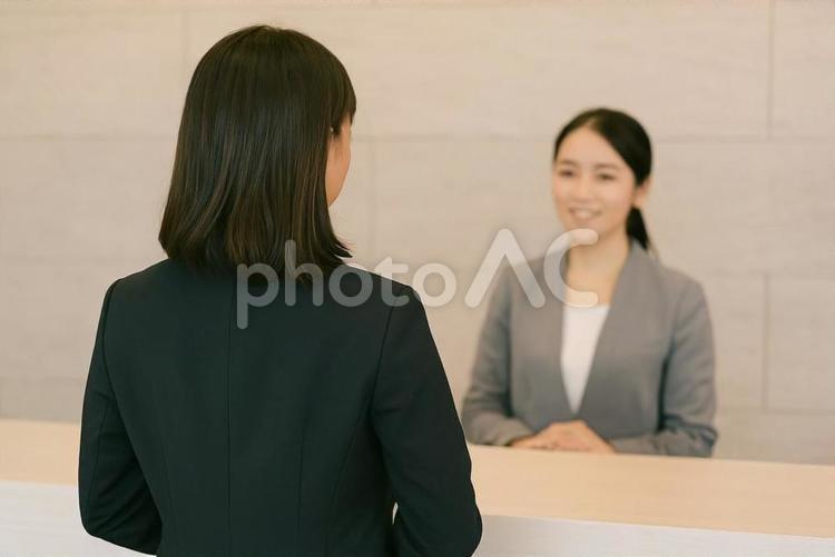 受付で来客対応する女性社員の後ろ姿 受付,カウンター,来客対応の写真素材