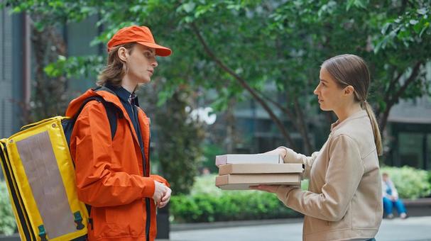 屋外でピザのデリバリーを受け取った女性の写真