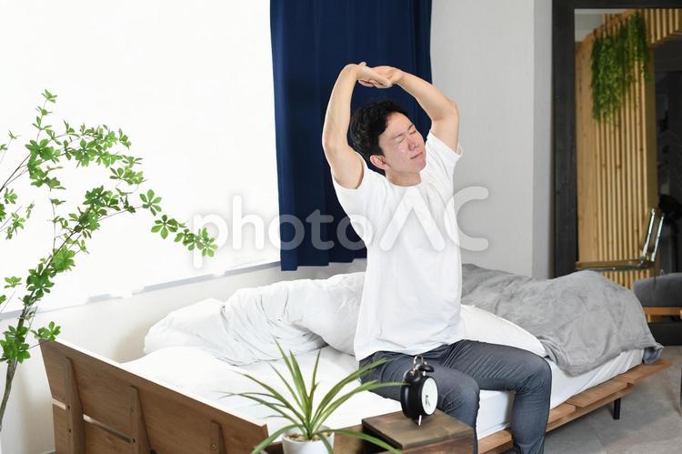 起床後にベッドの上でストレッチをする男性 ベッド,起床,男性の写真素材