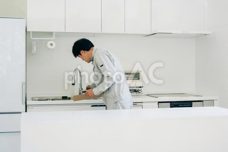 キッチンと作業着姿の男性（水道） 水道屋,水漏れ,漏水の写真素材