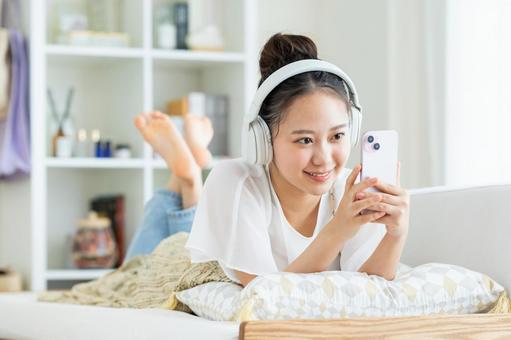 リビングでくつろぐ若い女性 リビングでくつろぐ若い女性 スマートフォン,笑顔,女性の写真素材