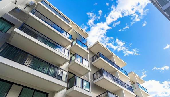 マンションを見上げる 青空背景 マンションを見上げる 青空背景の写真