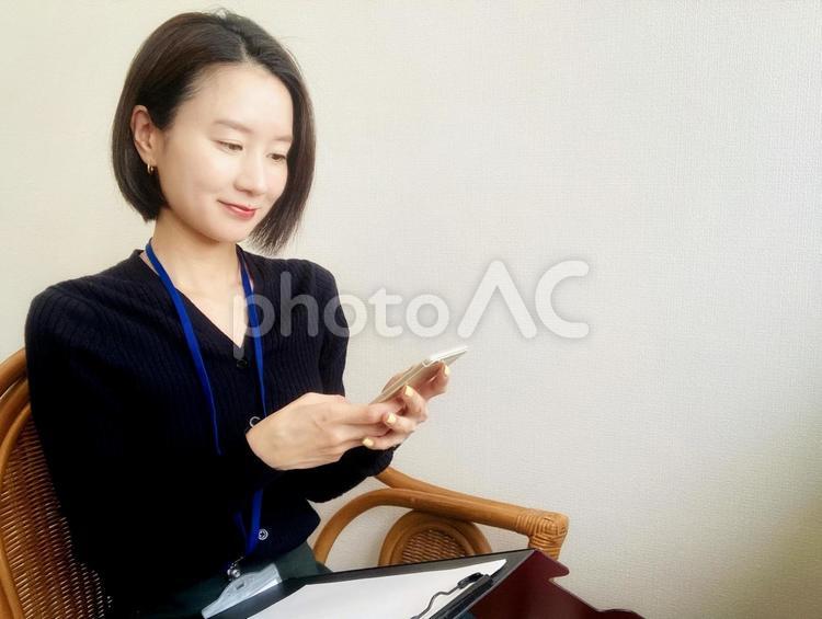 携帯を見ながらメモをとる社会人女性 女性,笑顔,微笑みの写真素材