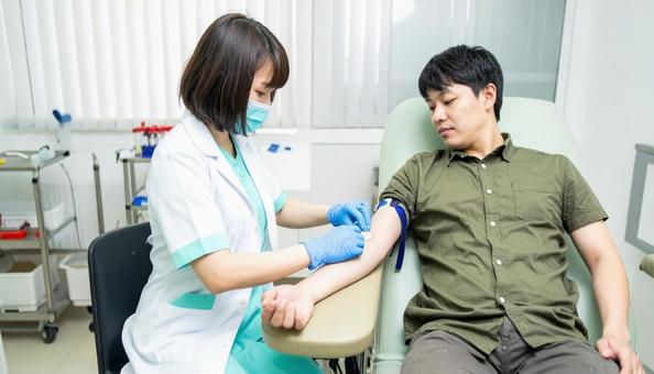 診察室で患者の腕に採血する医者 診察室で患者の腕に採血する医者の写真