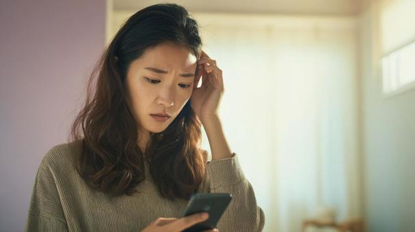 スマホに戸惑う女性 スマホに戸惑う女性の写真