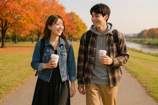 紅葉している河川敷を歩くカップルの写真