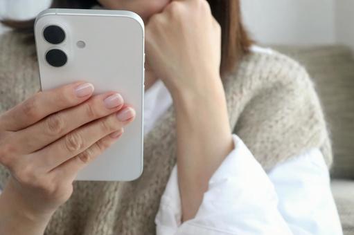 スマホを見ながら考える女性 スマホ,女性,悩むの写真素材