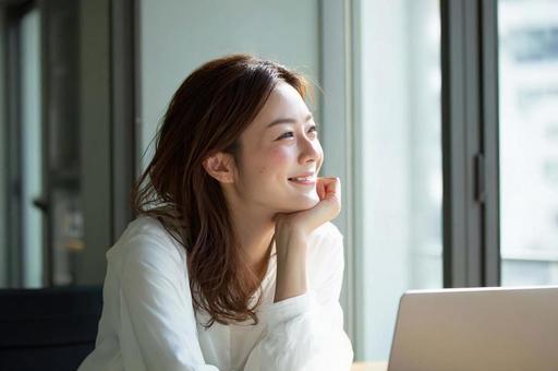 デスクでほほ笑むビジネス女性 デスクでほほ笑むビジネス女性の写真