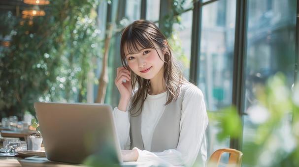 緑豊かなカフェでノートPCを使用する女性 緑豊かなカフェでノートPCを使用する女性の写真