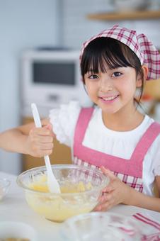 生地を混ぜながら微笑む子どもの表情 女の子,小学生,日本人の写真素材