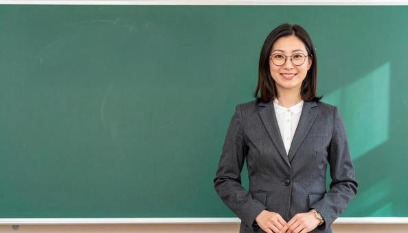 黒板前に立つ女性教師 黒板前に立つ女性教師の写真