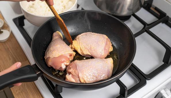 フライパンで鶏肉を炒める女性の手 フライパンで鶏肉を炒める女性の手の写真