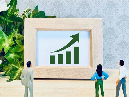 上昇中のグラフを見ながら議論する会社員の写真