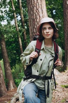 森の中でリュックを背負って立つ女の写真