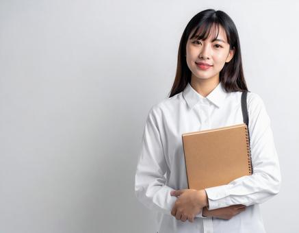 ノートを持って微笑む真面目な女子学生 ノートを持って微笑む真面目な女子学生の写真