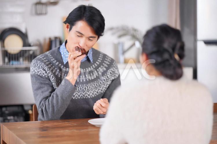 カヌレを食べながら話をしているカップル 男性,カップル,夫婦の写真素材