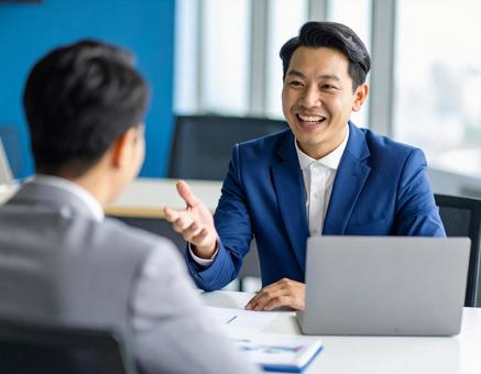 商談中に笑顔で話すビジネスマン 商談中に笑顔で話すビジネスマンの写真