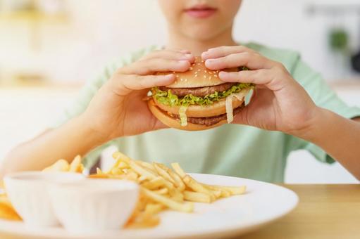 ハンバーガーを持ち上げる男の子の手元と日差し ハンバーガーを持ち上げる男の子の手元と日差しの写真