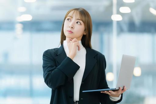 パソコンを持って考える女性ビジネスマン 女性,パソコン,考えるの写真素材