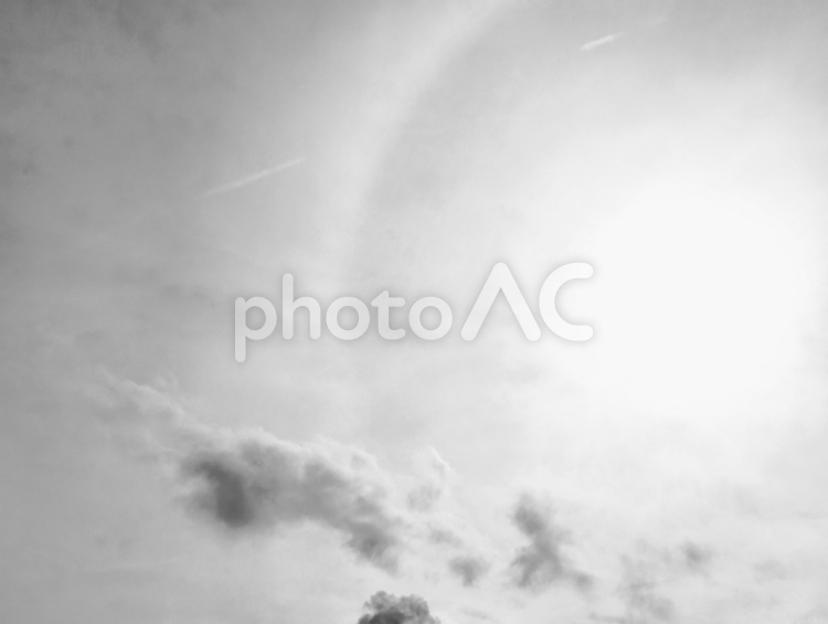 眩しく照りつける太陽と黒い雲の白黒写真 太陽,空,レンズフレアの写真素材