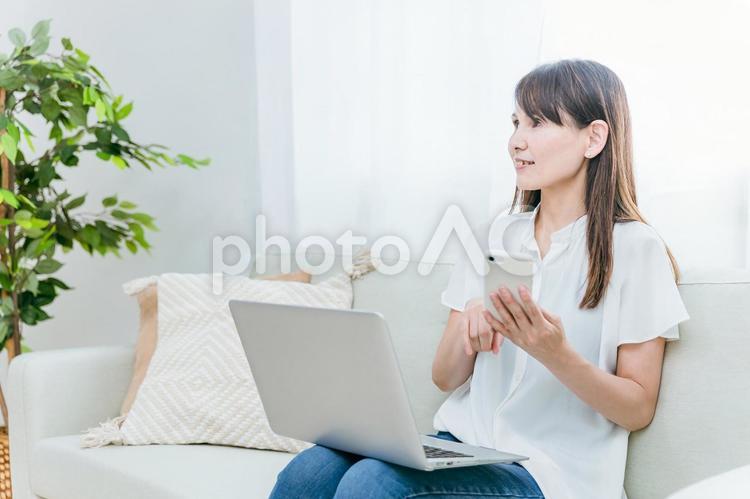 パソコンとスマホを使うミドル世代の女性 スマホ,テレワーク,スマートフォンの写真素材