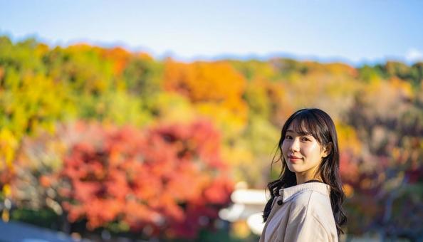 紅葉を背景に微笑む若い女性 紅葉を背景に微笑む若い女性の写真
