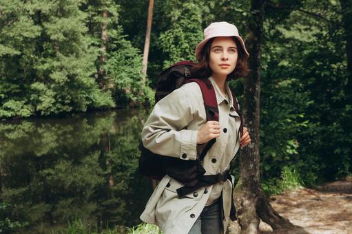 湖畔の近くでリュックを背負い振り向く女性の写真
