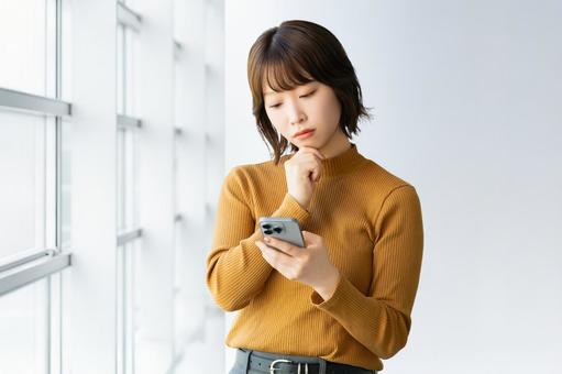 スマホを見て考える女性・ビジネスウーマン スマホを見て考える女性・ビジネスウーマン 女性,困る,考えるの写真素材