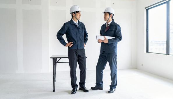 立ちながら話す作業着を着たビジネスマン 立ちながら話す作業着を着たビジネスマンの写真