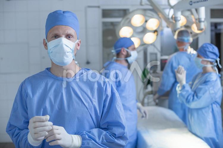 手袋を触るカメラ目線の男性 腕組み,手術,医師の写真素材