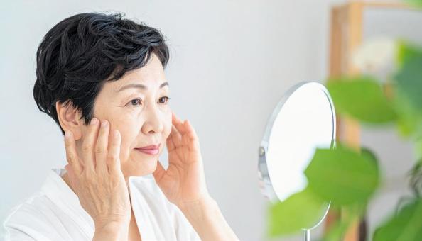 ほうれい線を気にして肌を触る中年の女性 ほうれい線を気にして肌を触る中年の女性の写真