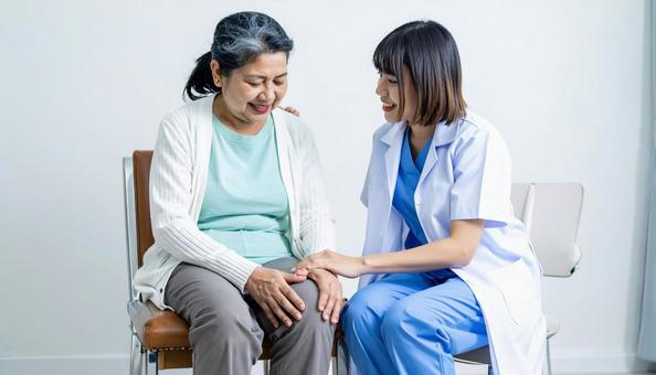 シニア女性の膝をマッサージする白衣の女性 シニア女性の膝をマッサージする白衣の女性の写真