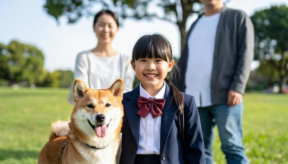 公園の芝生に立つ制服の子供と両親と愛犬 公園の芝生に立つ制服の子供と両親と愛犬の写真