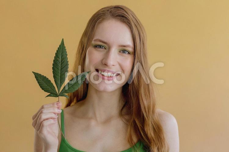 葉っぱを持ち笑顔の女性 女性,笑顔,葉っぱの写真素材