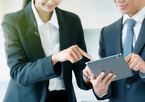 タブレット端末を確認する男女 タブレット端末を確認する男女の写真
