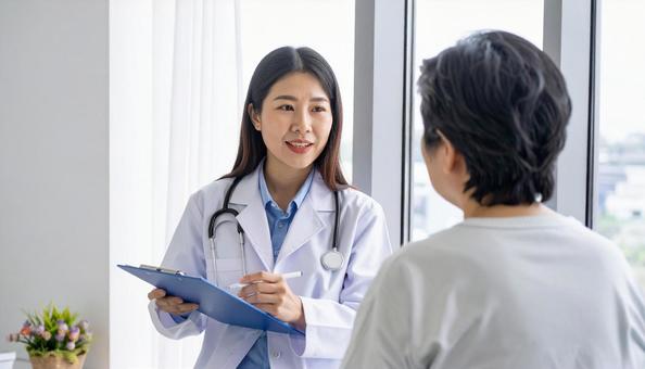 患者女性に説明する日本人医師の写真